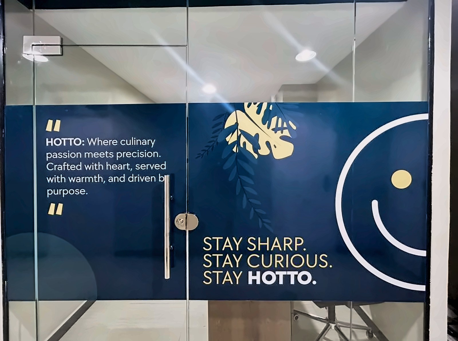 Installed Stay Hotto glass graphic with a smiling face motif